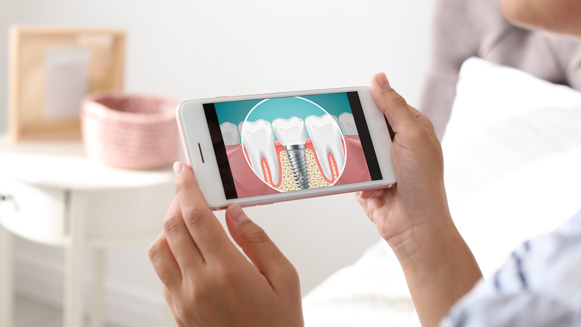 The image shows a person holding a smartphone displaying an illustration of a tooth with a cavity being filled, indicating dental care or treatment.