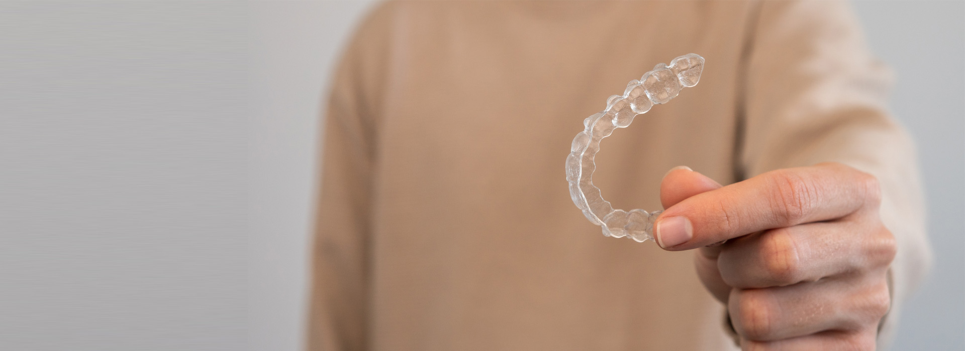 The image shows a hand holding a clear plastic loop with a small hole at its center.