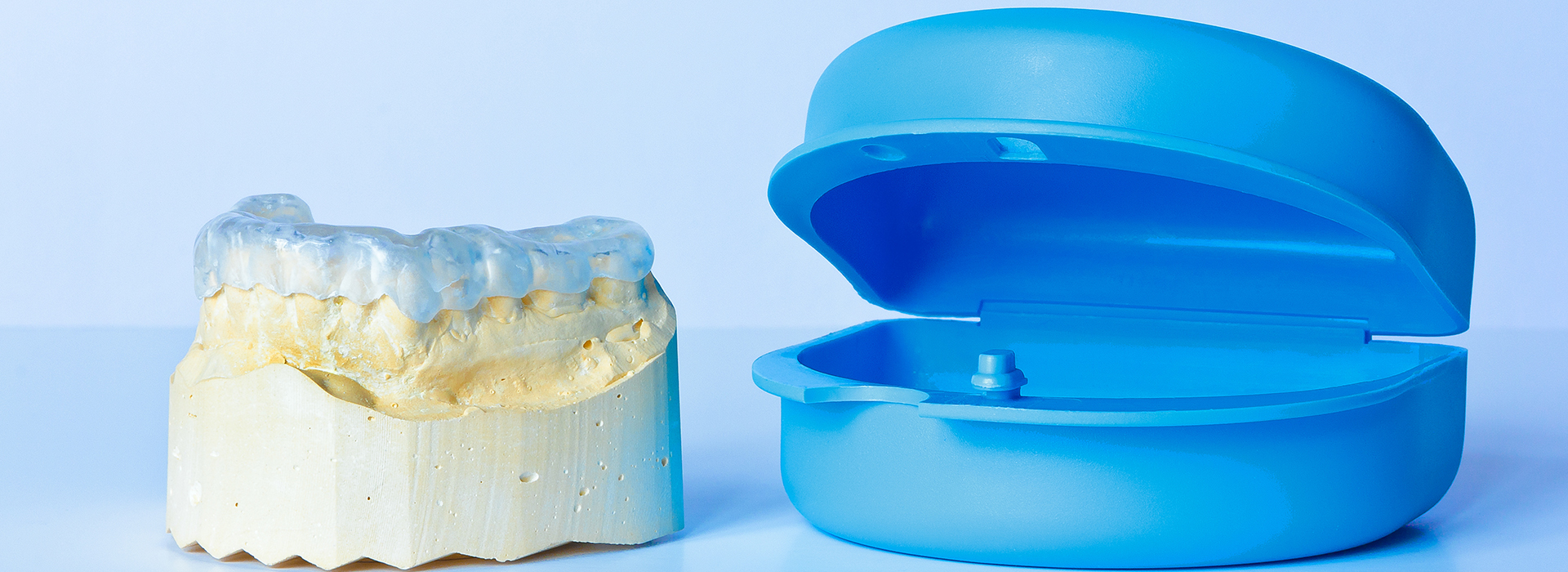 The image shows a blue toothbrush head next to a yellow dental implant, with both items placed on a white surface.