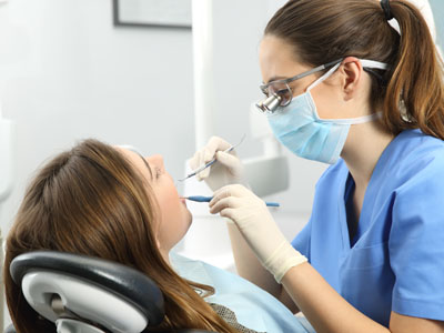 The image shows a dental professional performing a procedure on a patient s teeth while seated in a dental chair.