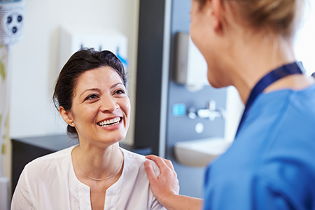 This is a split-screen photograph showing two different scenes  on the left, a woman wearing a white shirt stands next to another woman who appears to be laughing  on the right, a nurse in blue scrubs smiles at a woman with dark hair, who seems to be receiving medical attention or advice.
