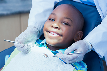 A young boy sitting in a dentist s chair with a smile, receiving dental care from a professional.