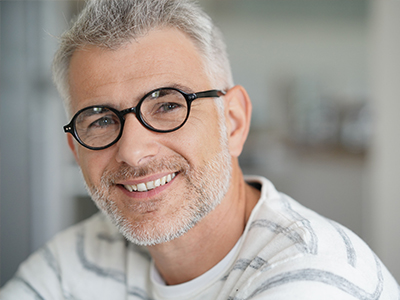 Man with glasses smiling at camera.