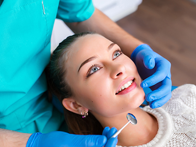 A young woman with blue eyes receiving dental care while wearing a surgical mask.
