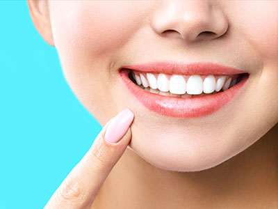 The image shows a close-up of a person s face with a bright smile, highlighting their teeth and lipstick.